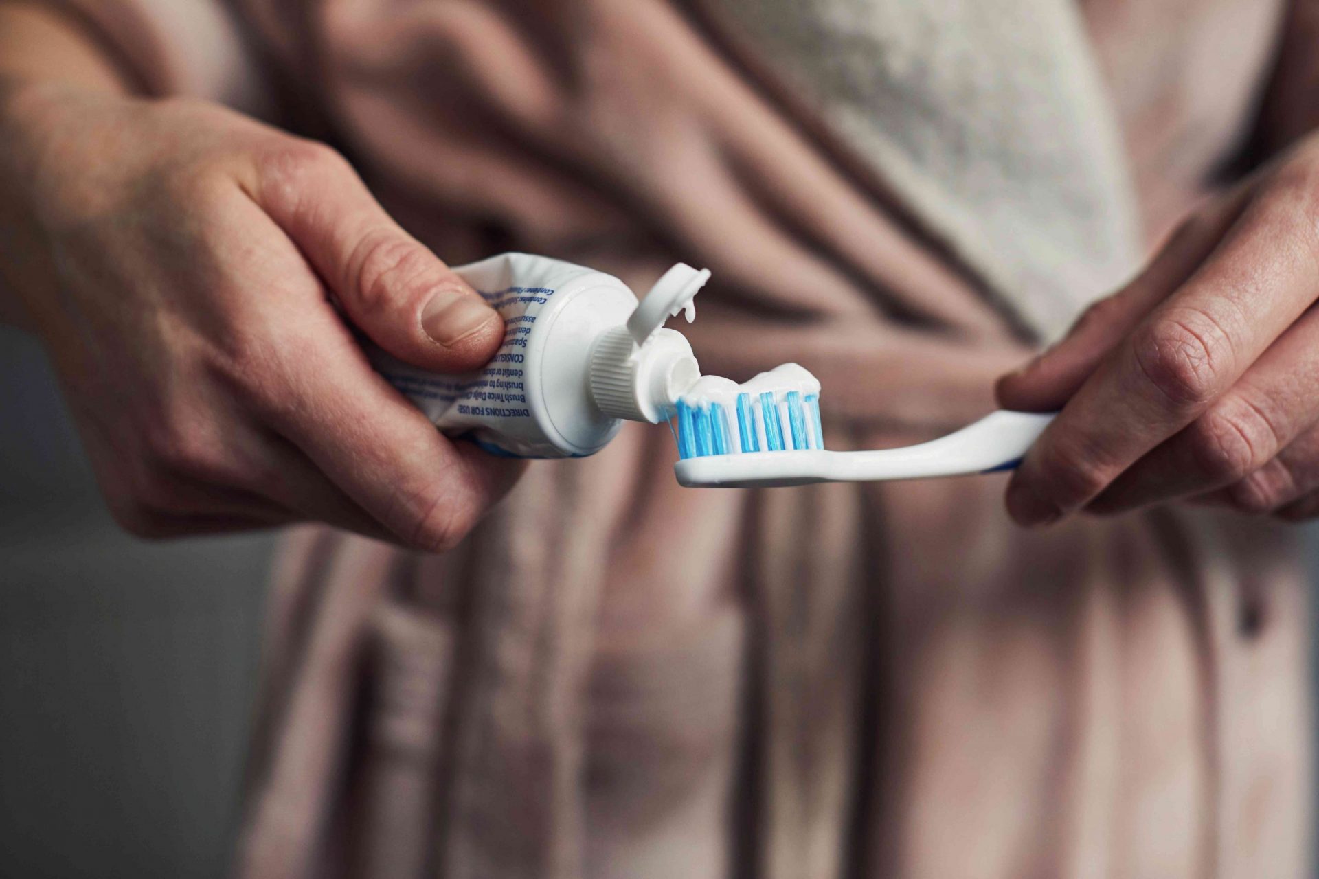 Mujer poniendo pasta de dientes en un cepillo