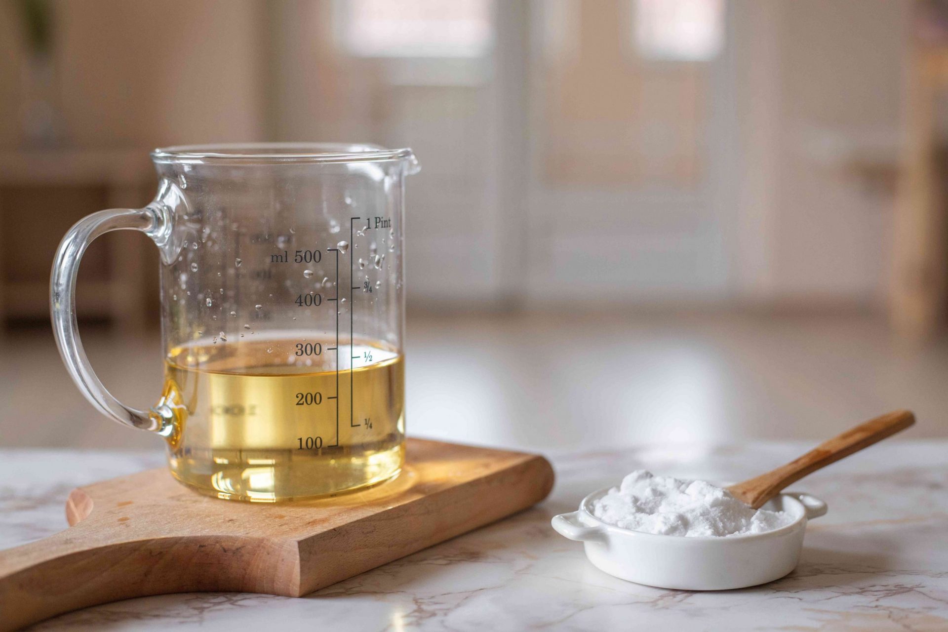 foto de producto de vinagre de sidra de manzana en un tarro medidor con bicarbonato de sodio en un recipiente pequeño con una cuchara de madera