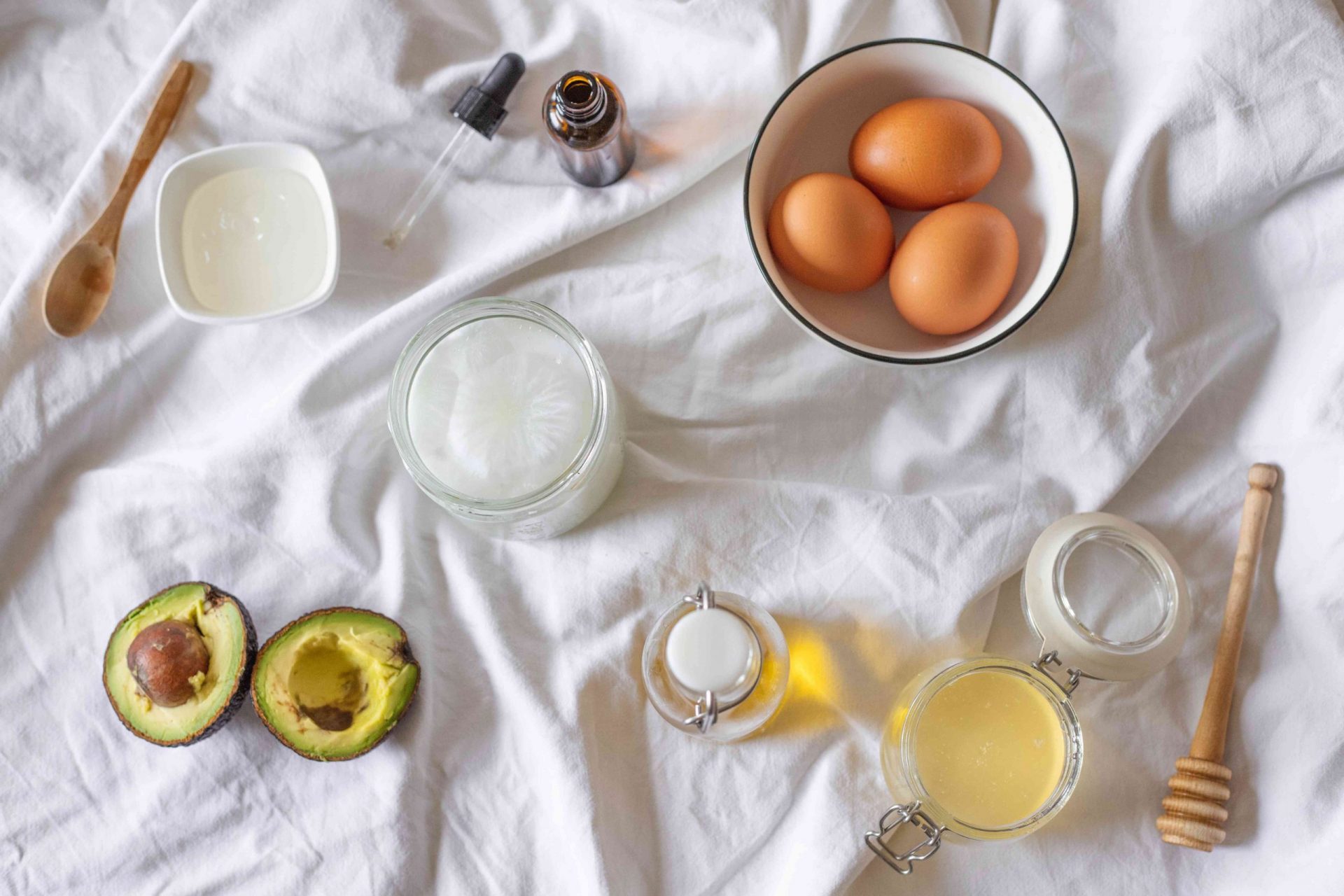 plano de los ingredientes utilizados para hacer la mascarilla capilar DIY: huevos, aguacate, aceite de coco, etc.